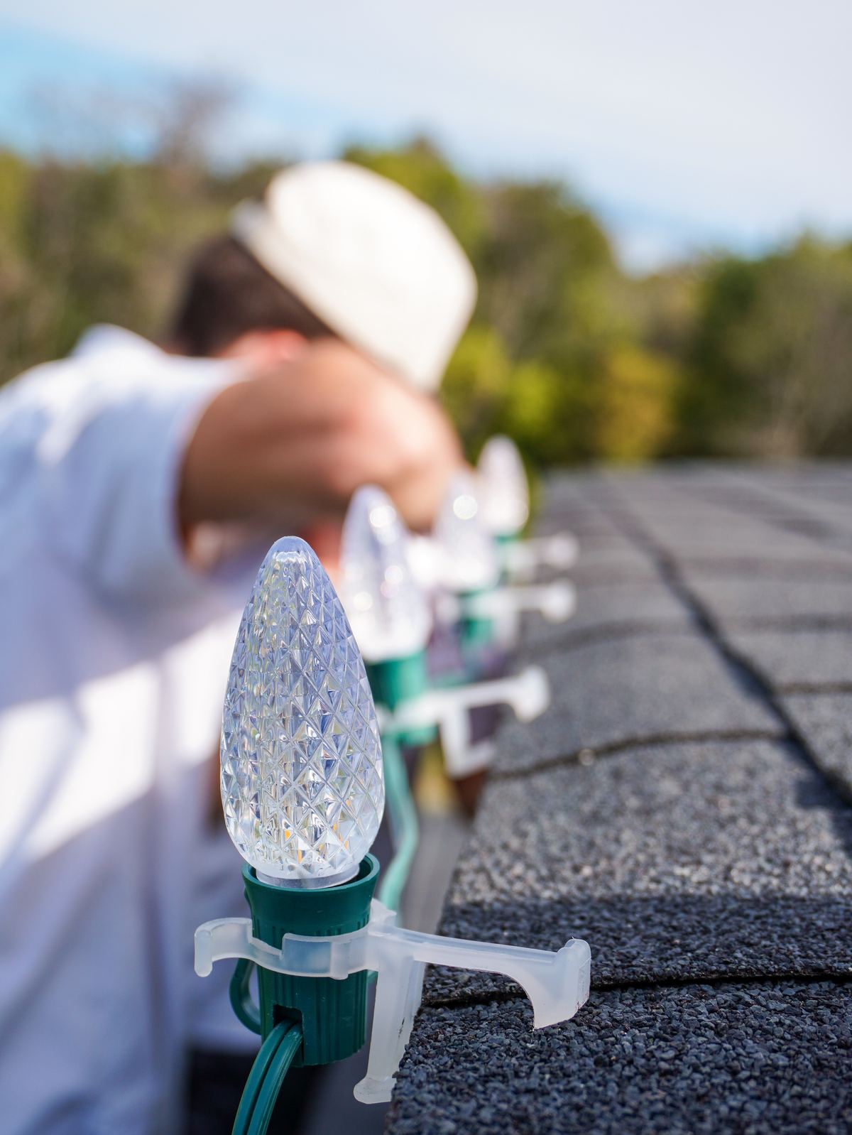 Close-up of a C9 holiday bulb clipped to the shingle roofline during installation