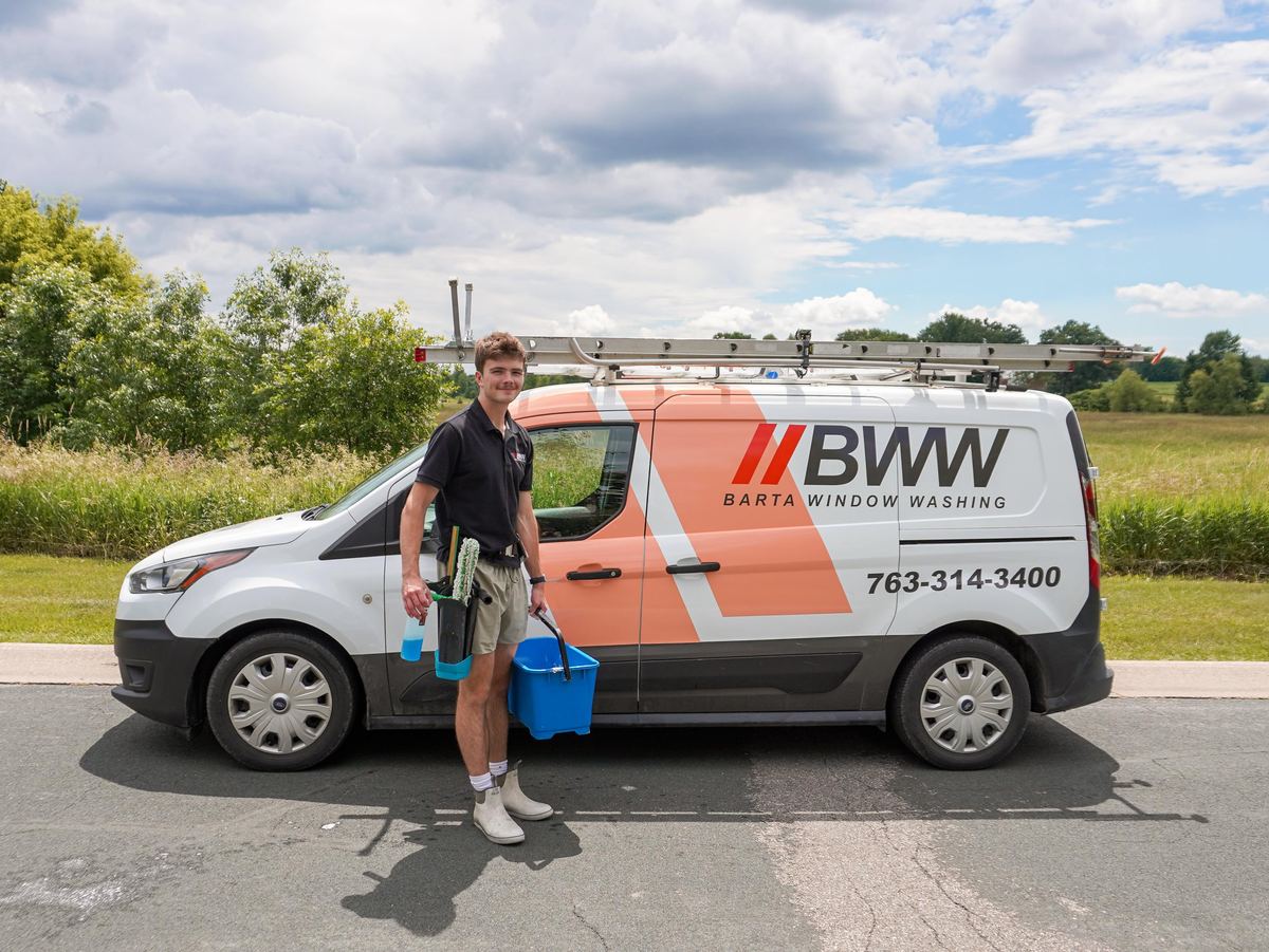 Technician setting down buckets beside the Barta Window Washing van on a rural road