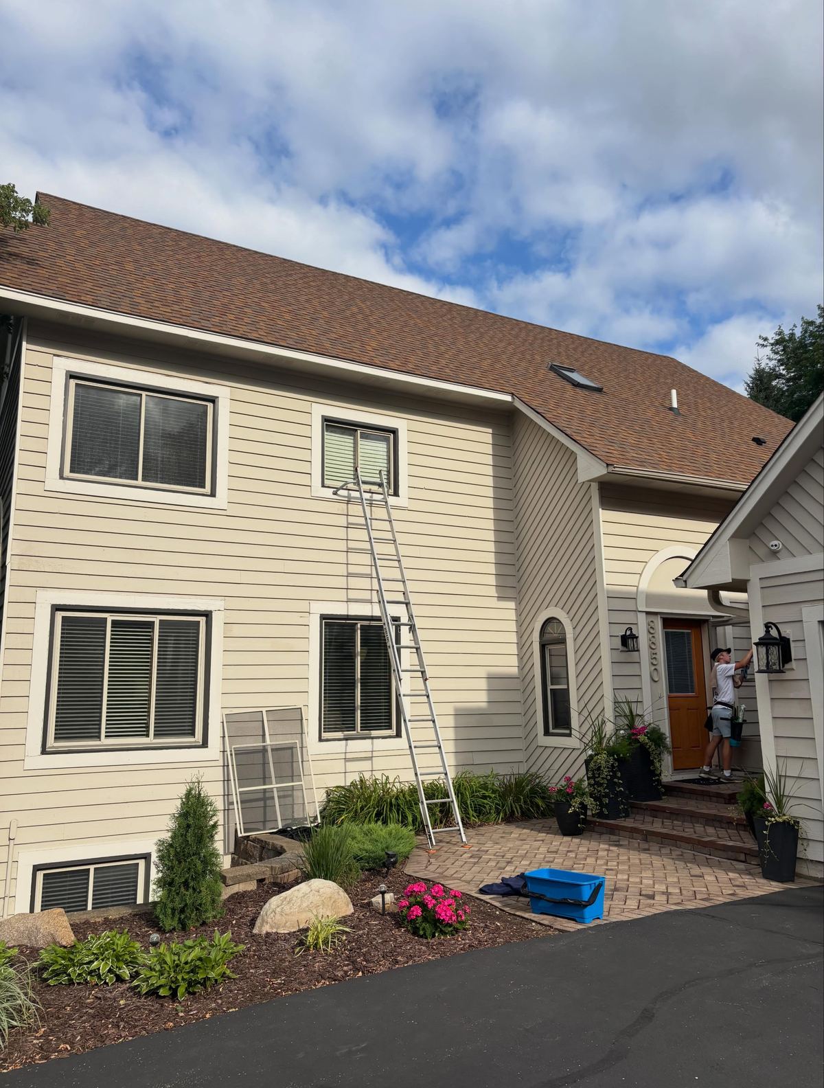 Extension ladder staged against a tall home for upper-window cleaning