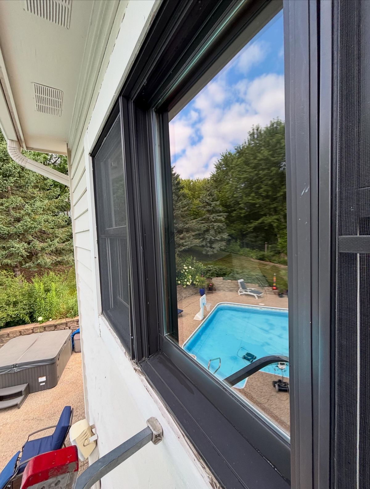 View over a backyard pool through a just-cleaned open window