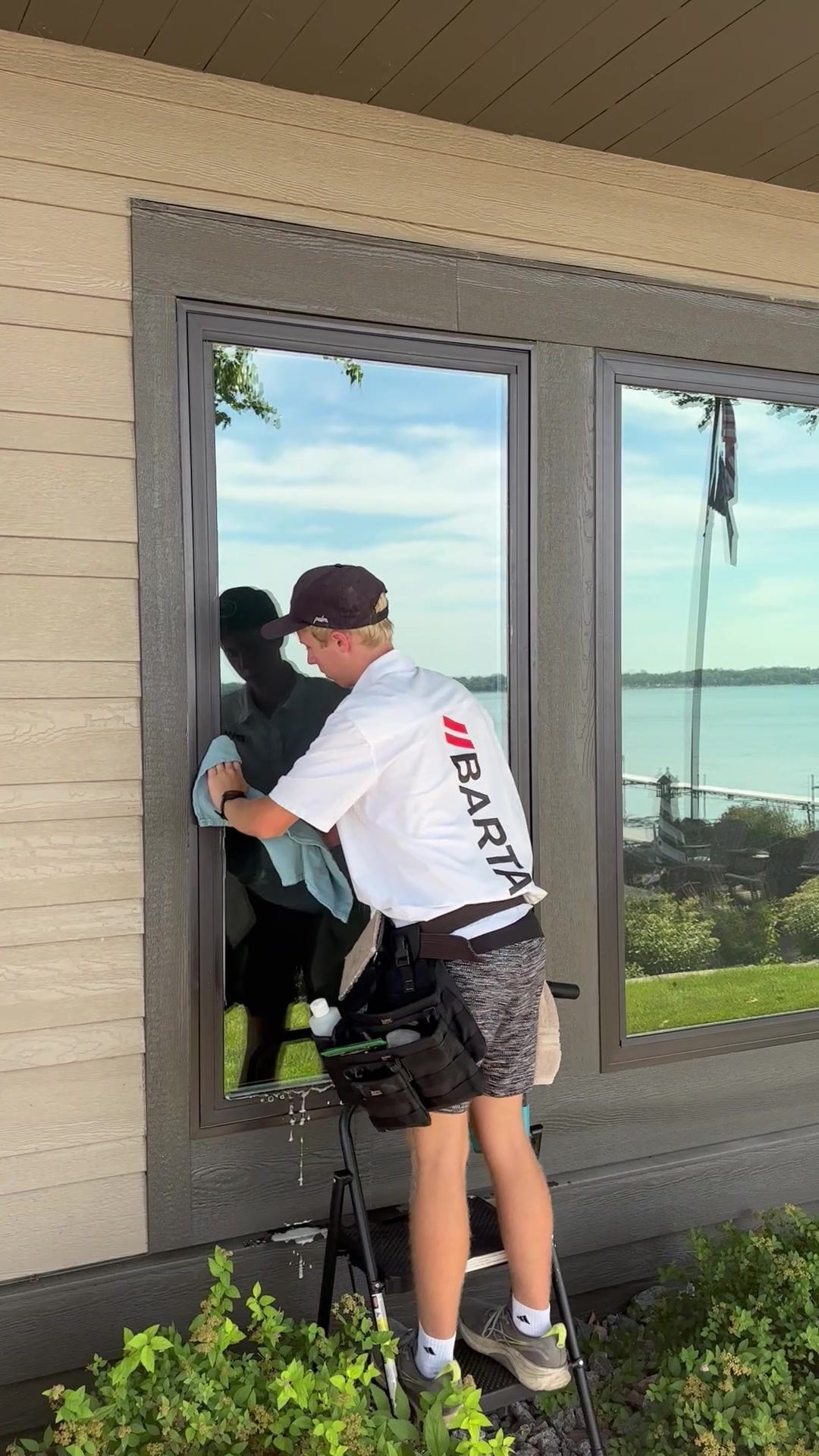 Barta technician hand-detailing a lake-facing window at a Buffalo lake home