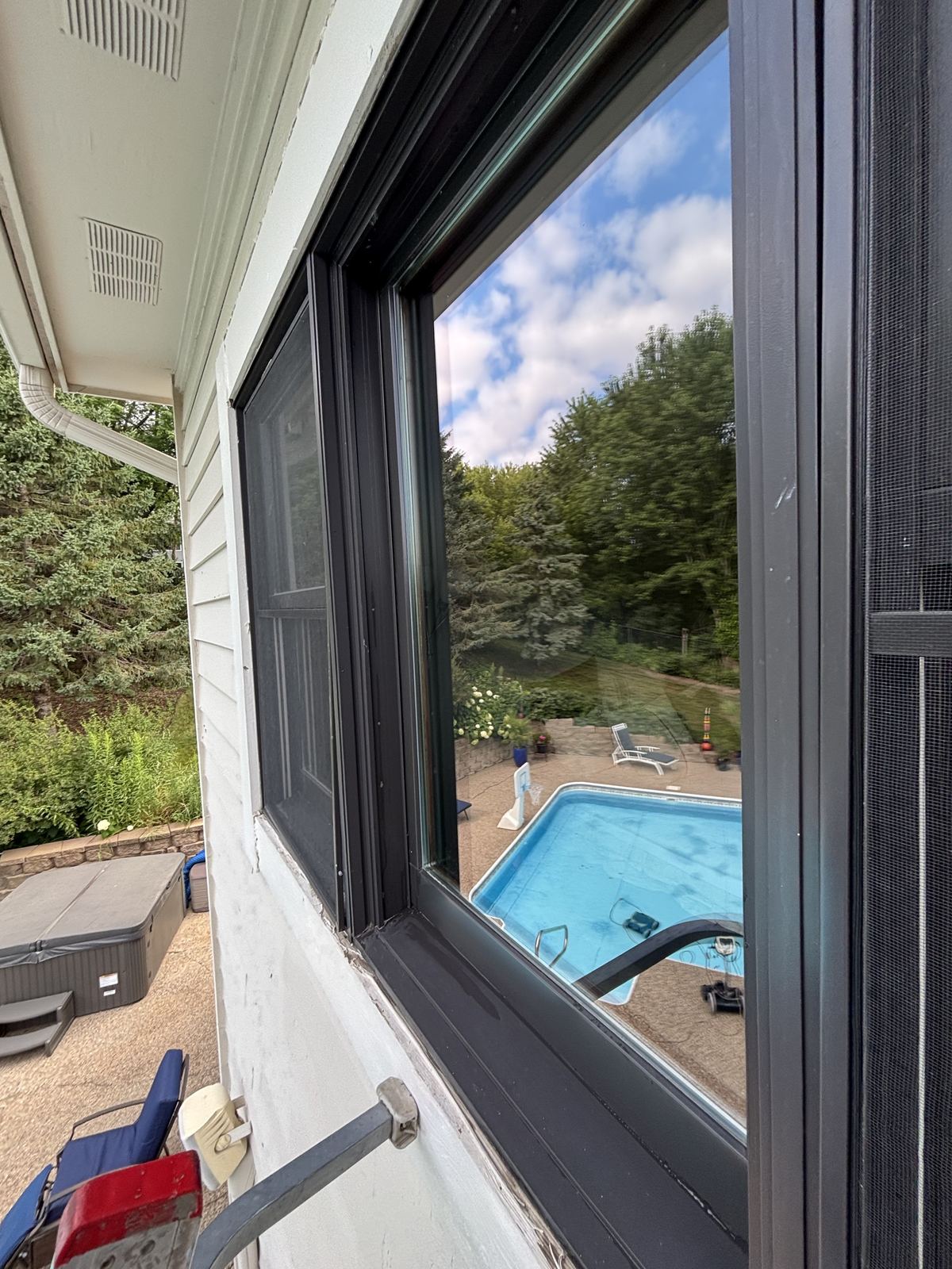 A freshly cleaned window on a Chanhassen home, with the backyard pool reflected in the glass