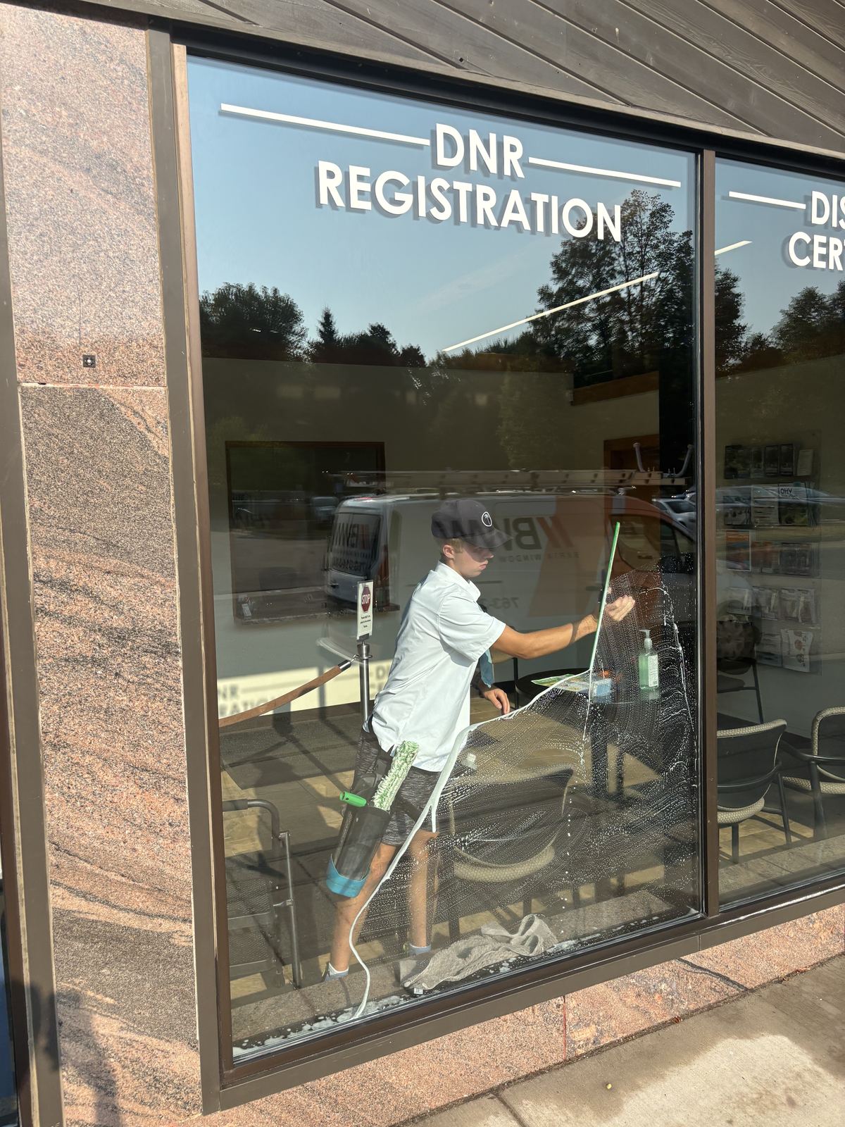 Barta crew member squeegeeing the inside of a large storefront window in downtown Delano