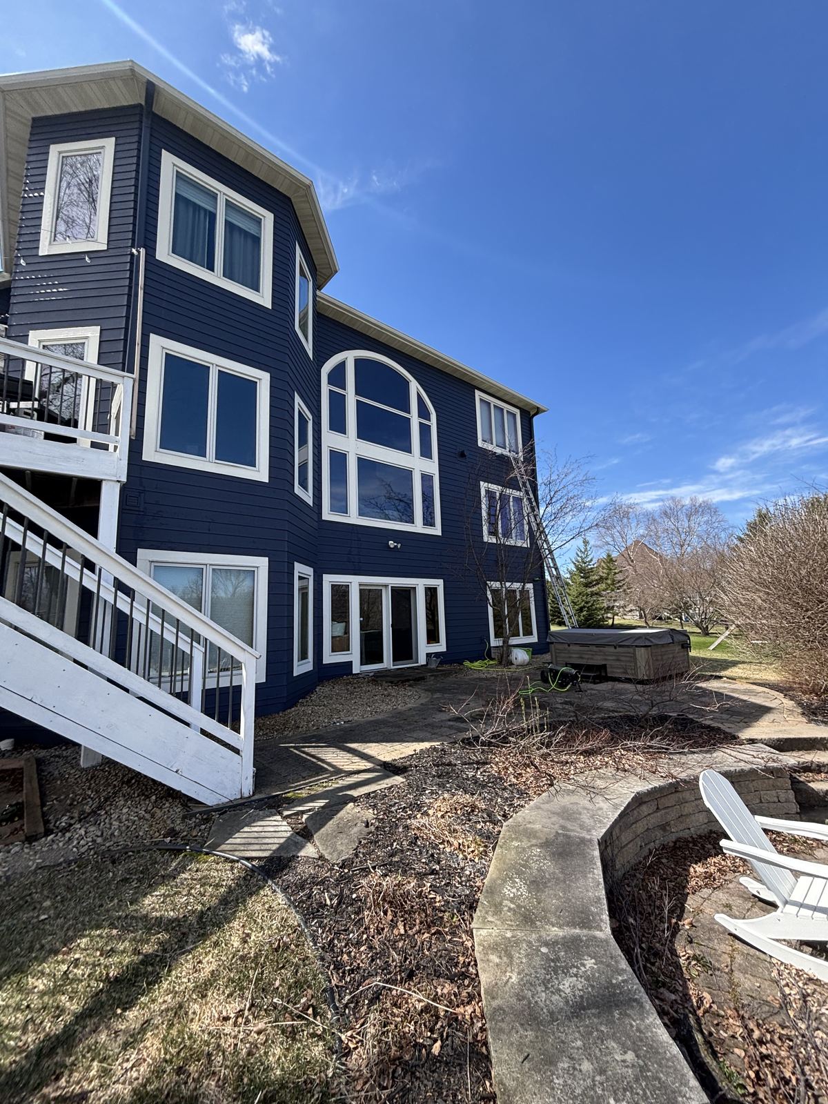 The back of a three-level Independence home with arched windows, mid-cleaning with a ladder
