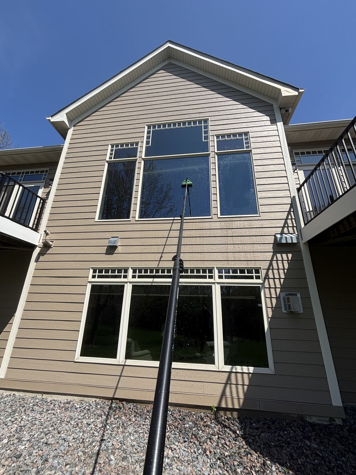 Water-fed pole cleaning the gable windows of an Independence home