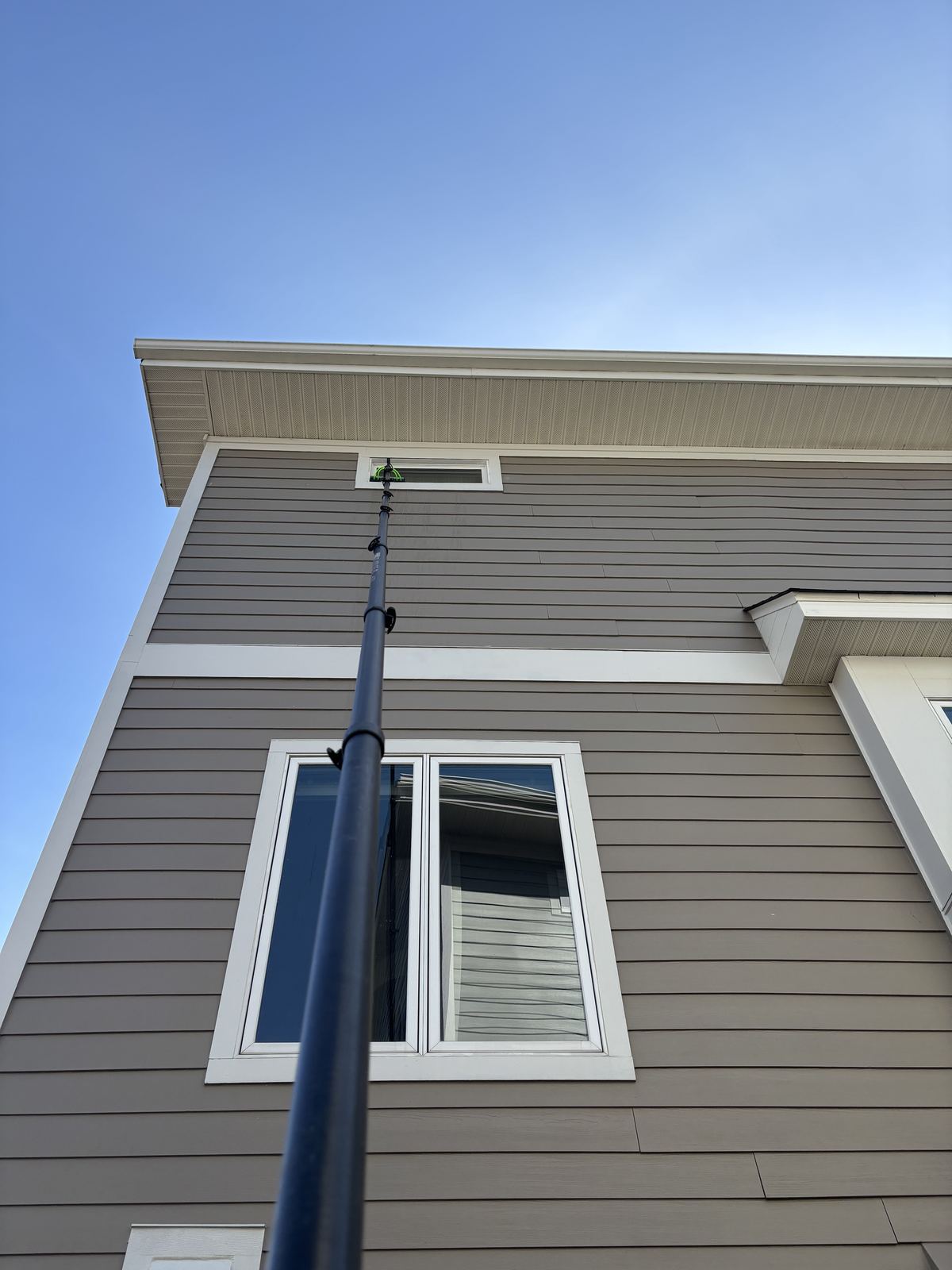 Water-fed pole reaching a high gable window on an Orono home