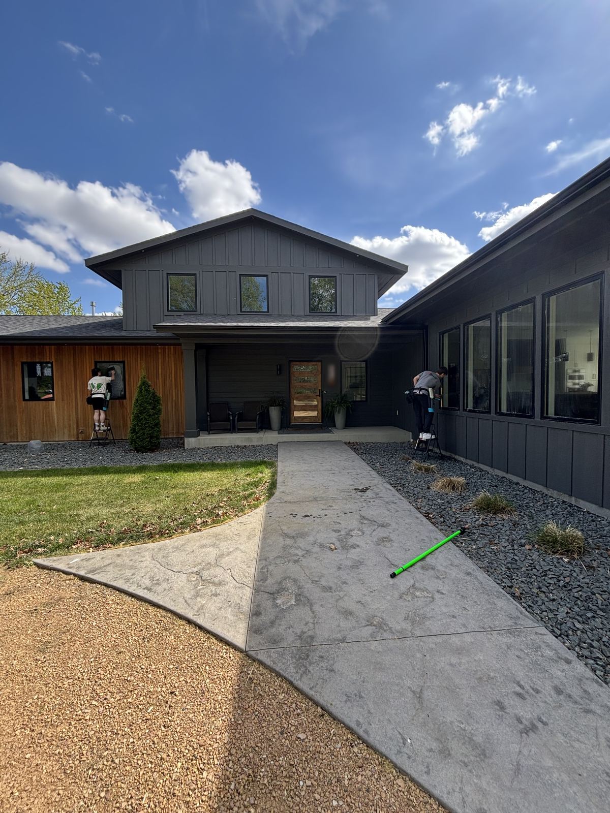 Two Barta technicians cleaning the front windows of a modern Waconia home