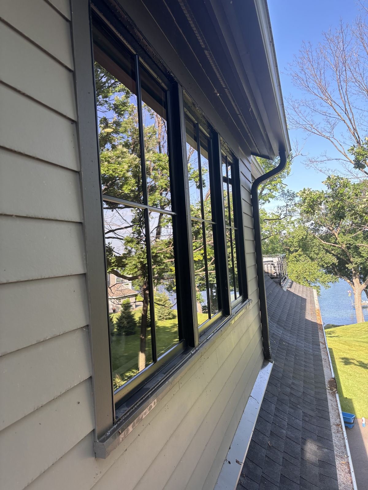 Freshly cleaned black-framed upper-story windows on a Wayzata lake home, with the lake behind