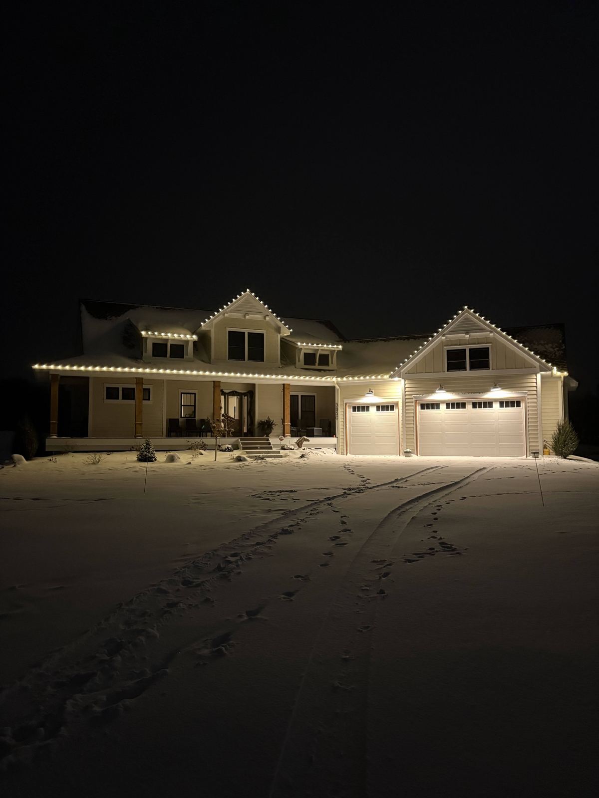 Warm white holiday lights installed along a home's roofline at night
