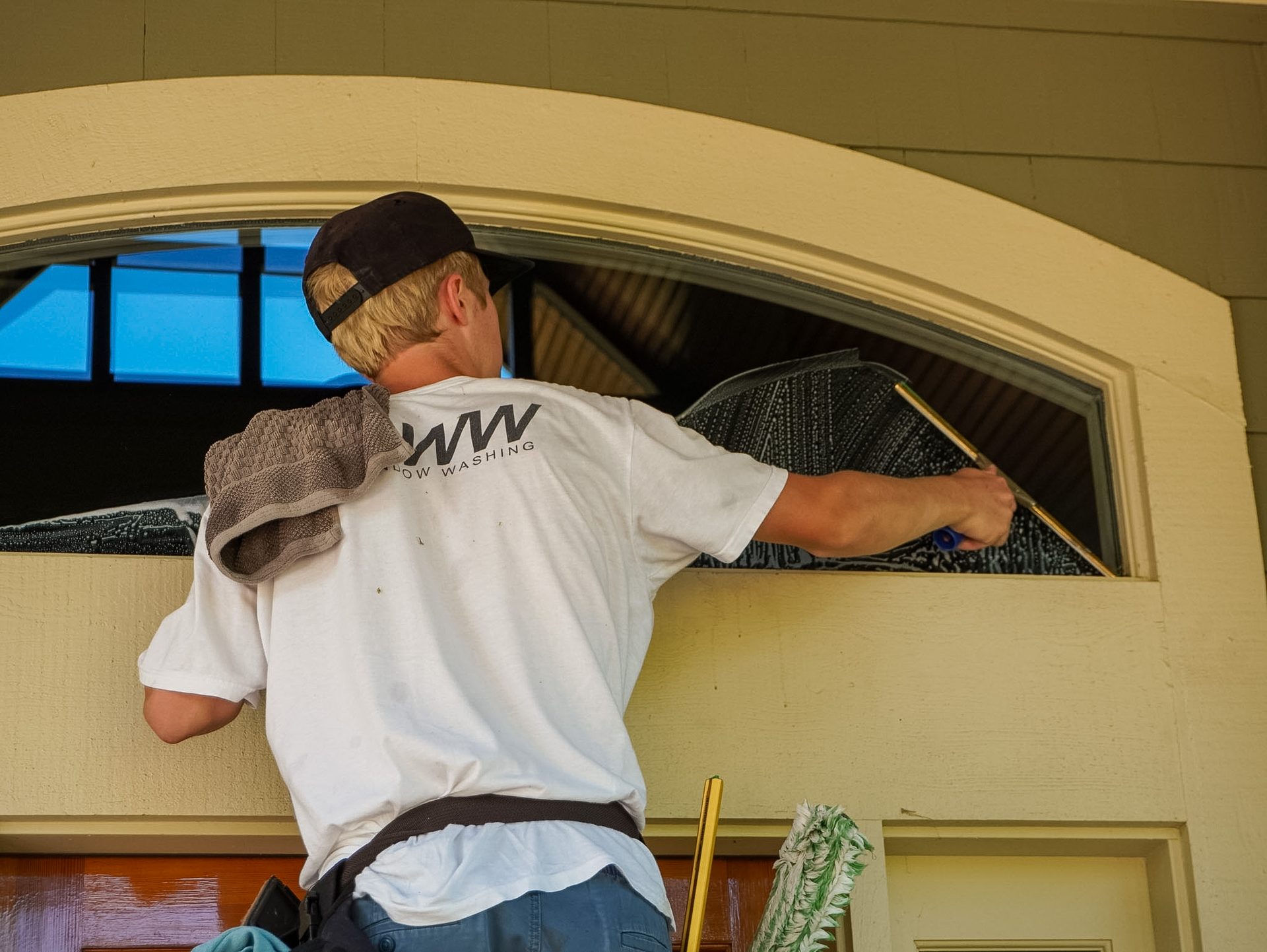 Close-up of a Barta Window Washing technician squeegeeing an arched window