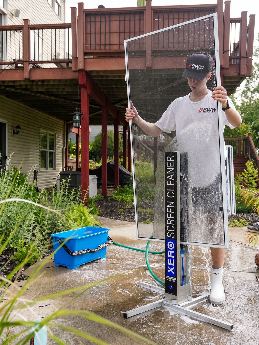 Technician washing a window screen at a screen-cleaning station